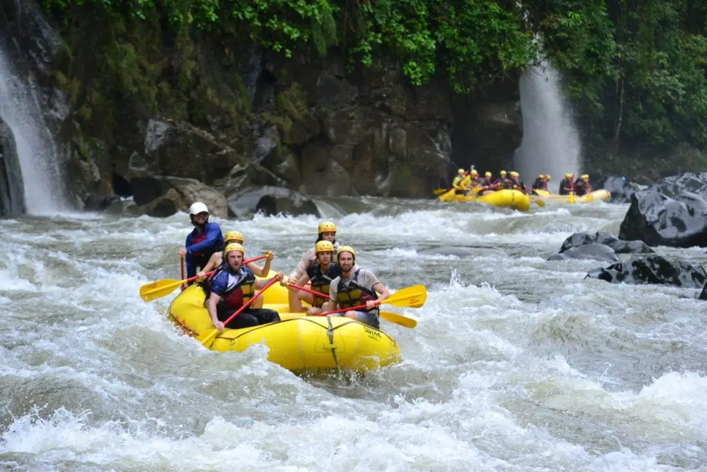 Top adventurous things to do in Costa Rica - white water rafting on Penas Blancas River with two waterfalls in the background